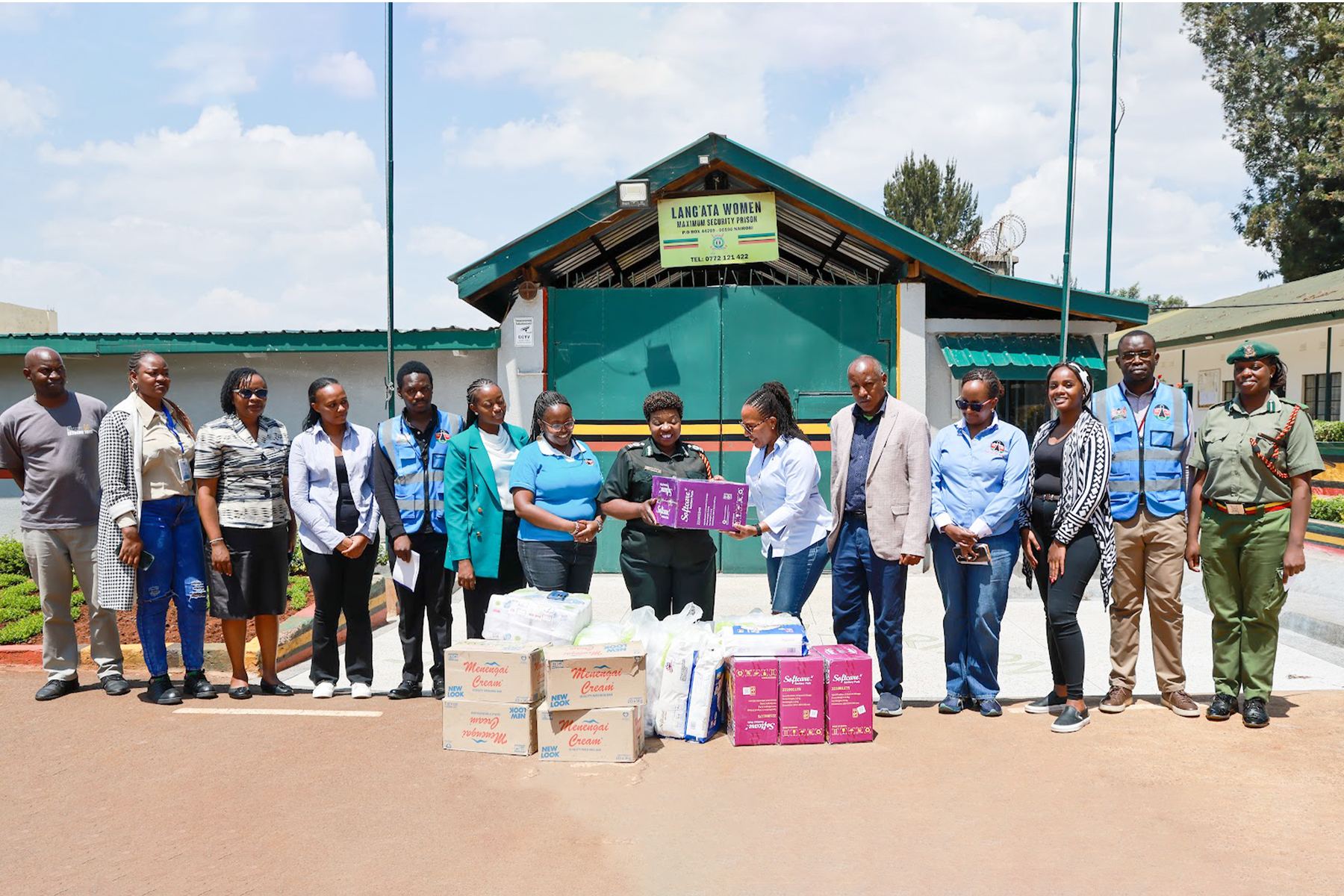 Commission officers and prison officers outside Lang'ata Women's Prison, with boxes of donated supplies in front of them.