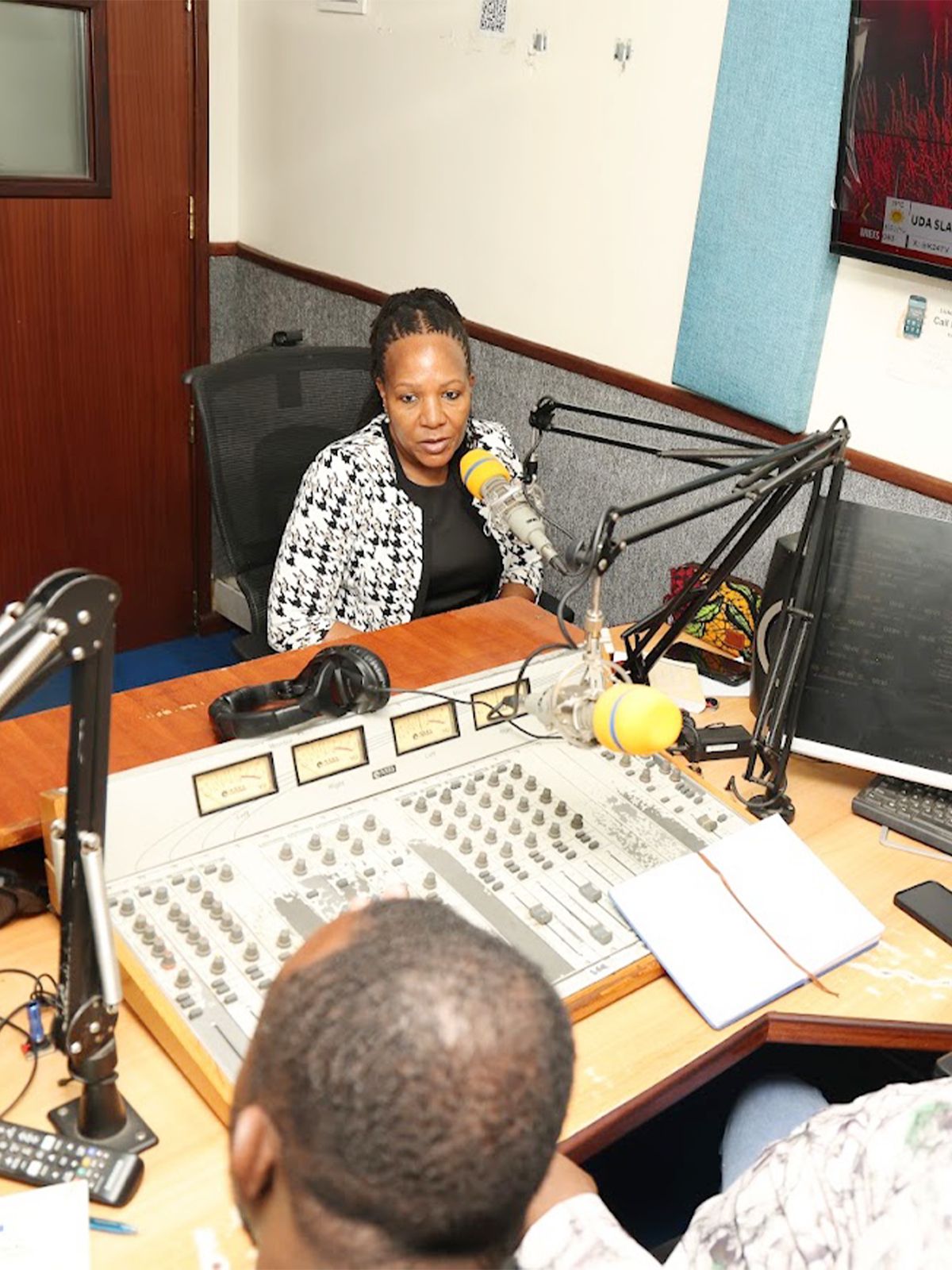 The Commission Secretary at a radio studio microphone during a public sensitisation broadcast.